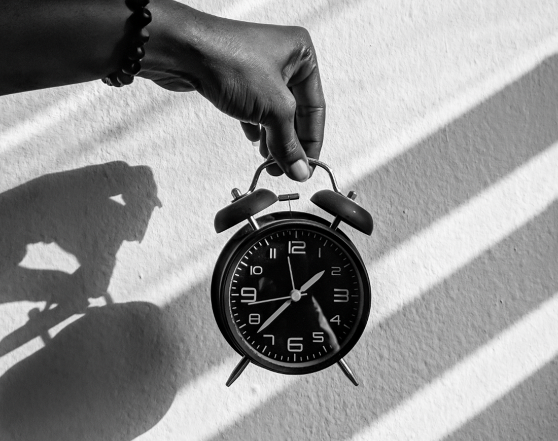 Clock in hand in front of wall